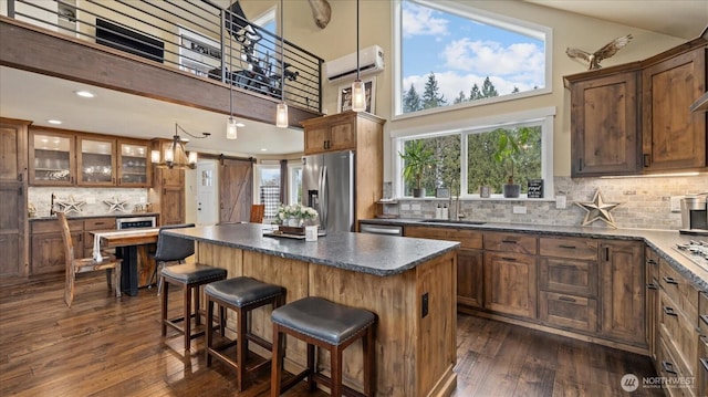 kitchen featuring dark wood finished floors, stainless steel appliances, dark countertops, a barn door, and a sink