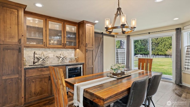 dining area featuring a healthy amount of sunlight, a barn door, beverage cooler, and dark wood-type flooring