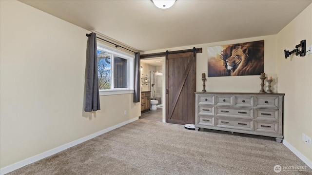 unfurnished bedroom featuring ensuite bath, carpet, baseboards, and a barn door