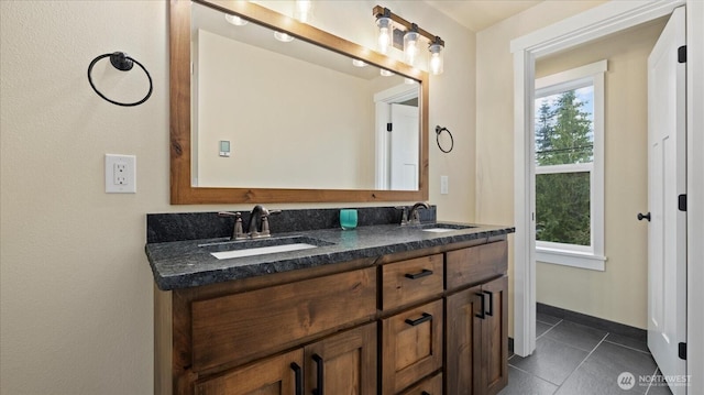 full bathroom featuring double vanity, baseboards, a sink, and tile patterned floors