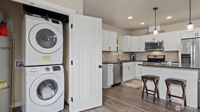 kitchen featuring stacked washer and dryer, appliances with stainless steel finishes, backsplash, and white cabinets