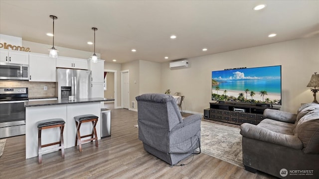 living room with a wall unit AC, wood finished floors, and recessed lighting