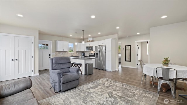 living room with recessed lighting, baseboards, and wood finished floors