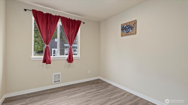 empty room with visible vents, baseboards, and wood finished floors