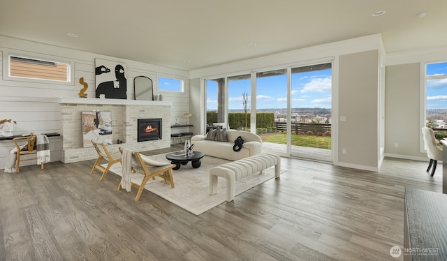 living room with a brick fireplace, baseboards, and wood finished floors