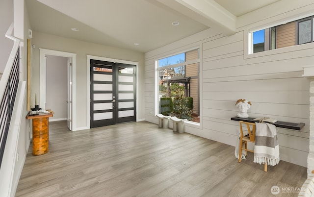 foyer featuring french doors, beam ceiling, and wood finished floors