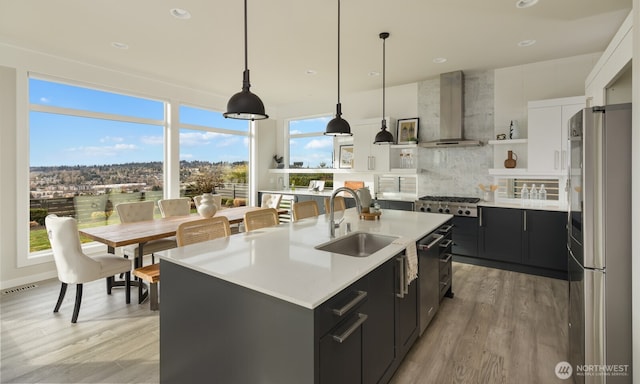 kitchen with stainless steel appliances, visible vents, wall chimney range hood, dark cabinetry, and open shelves