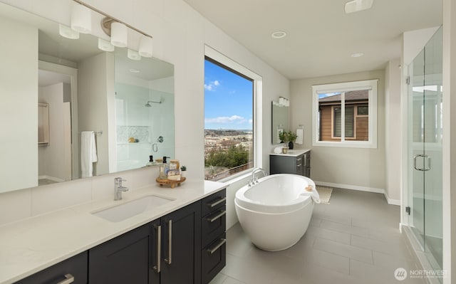 bathroom featuring two vanities, a stall shower, a sink, tile patterned flooring, and a freestanding tub