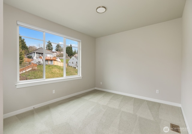 unfurnished room with light colored carpet and baseboards