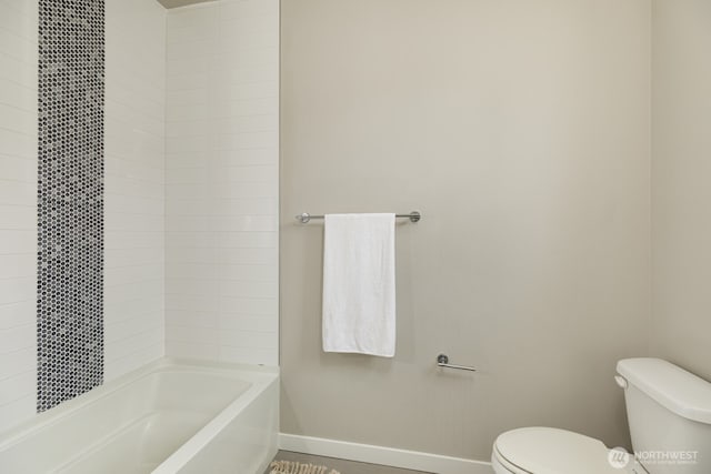 bathroom featuring toilet, baseboards, and shower / washtub combination