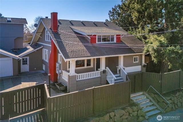 view of front facade featuring a porch, fence private yard, roof with shingles, and a chimney