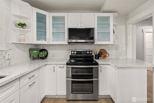 kitchen with white cabinets, light stone countertops, appliances with stainless steel finishes, and open shelves