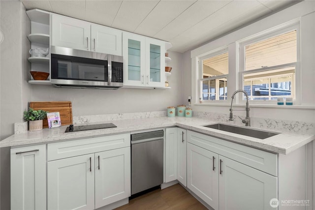 kitchen with open shelves, stainless steel appliances, glass insert cabinets, white cabinetry, and a sink