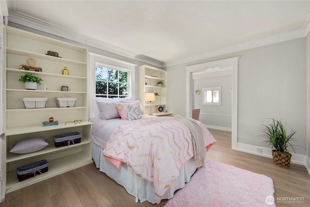 bedroom with crown molding, baseboards, and wood finished floors