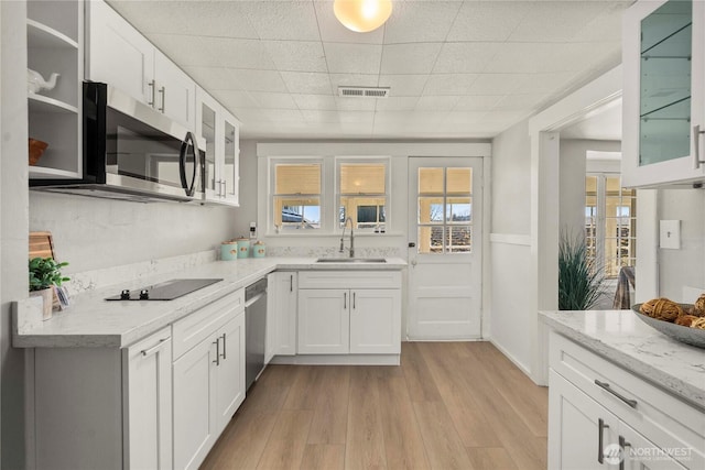 kitchen featuring stainless steel appliances, a sink, visible vents, white cabinetry, and light wood-type flooring