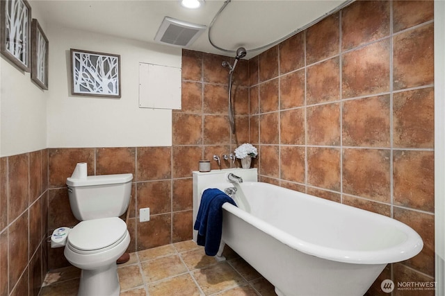 full bath with visible vents, tile walls, and toilet