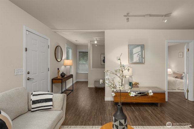 living area featuring track lighting, baseboards, and wood finished floors