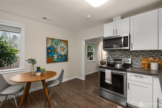 kitchen with dark countertops, a wealth of natural light, stainless steel appliances, and backsplash