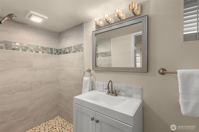 full bathroom with tiled shower and vanity