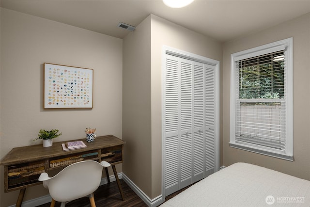 bedroom with a closet, wood finished floors, visible vents, and baseboards