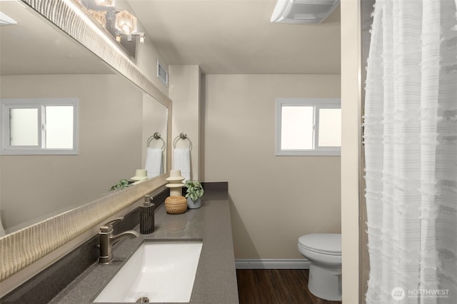 bathroom with a healthy amount of sunlight, visible vents, toilet, and wood finished floors