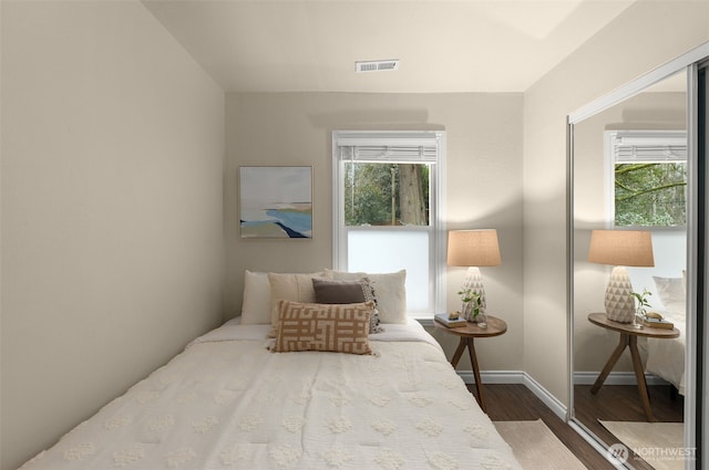 bedroom featuring multiple windows, wood finished floors, visible vents, and baseboards