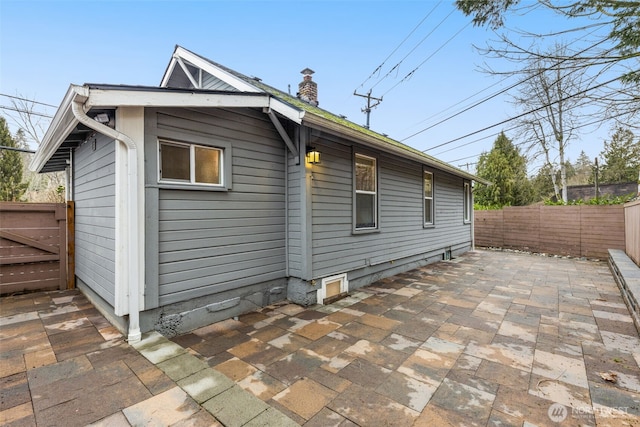 view of side of home featuring a patio, a chimney, and a fenced backyard