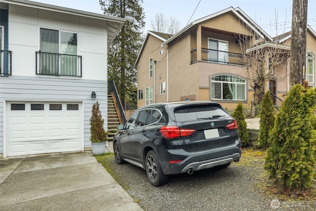 view of front of property with a garage, driveway, stairway, and stucco siding