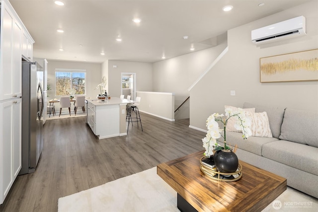 living area with recessed lighting, baseboards, dark wood-type flooring, and a wall mounted AC