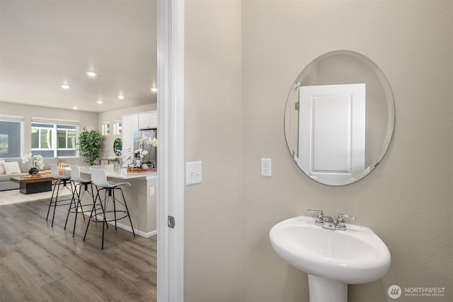 bathroom featuring recessed lighting, baseboards, a sink, and wood finished floors