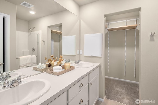 full bath featuring double vanity, visible vents, a sink, and walk in shower