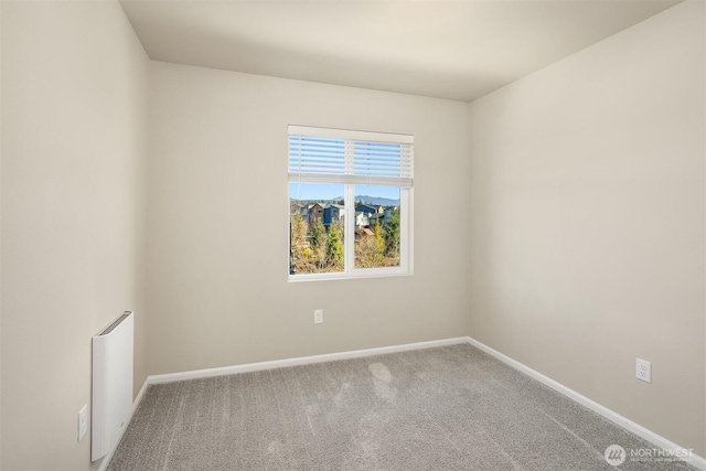 carpeted spare room featuring radiator and baseboards