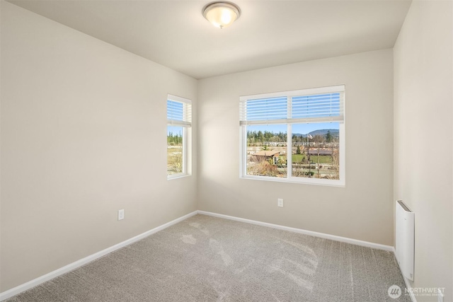 spare room featuring carpet floors, radiator heating unit, and baseboards