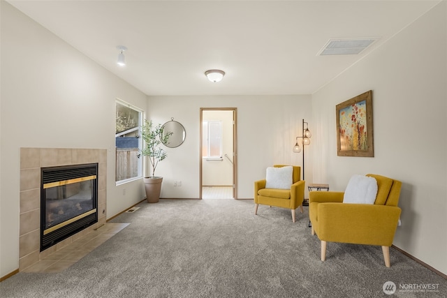 living area with baseboards, carpet flooring, visible vents, and a tiled fireplace