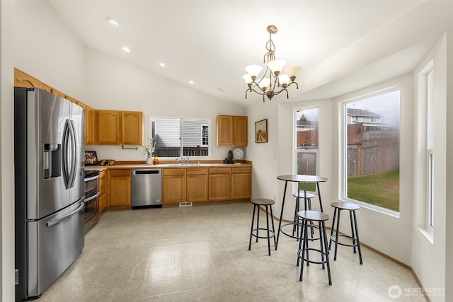 kitchen with stainless steel appliances, a sink, vaulted ceiling, hanging light fixtures, and light countertops