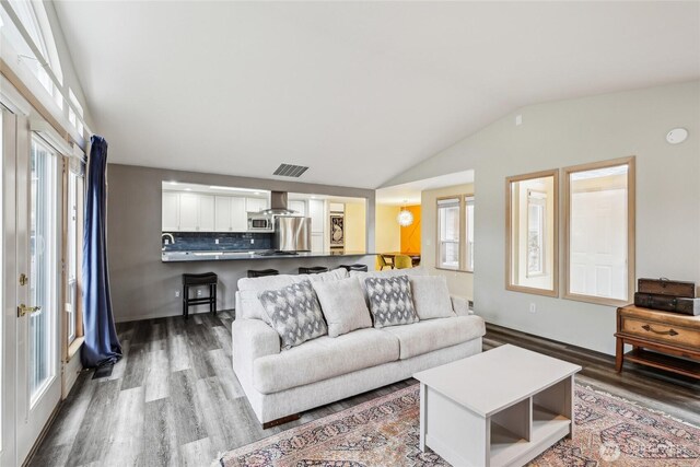 living room with lofted ceiling, wood finished floors, and visible vents