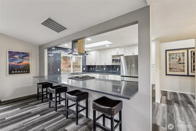 kitchen featuring island range hood, visible vents, white cabinets, appliances with stainless steel finishes, and backsplash