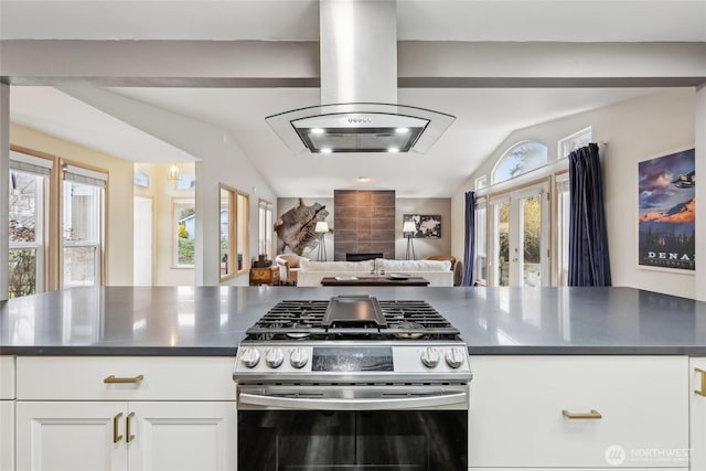 kitchen with island exhaust hood, dark countertops, open floor plan, white cabinets, and stainless steel gas range oven