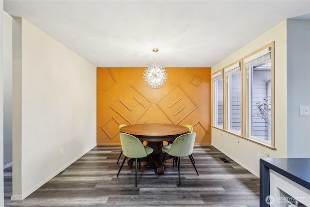 dining space with a chandelier, an accent wall, dark wood-type flooring, visible vents, and baseboards