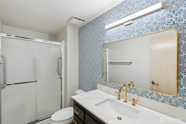 full bathroom with visible vents, toilet, a shower stall, vanity, and wallpapered walls