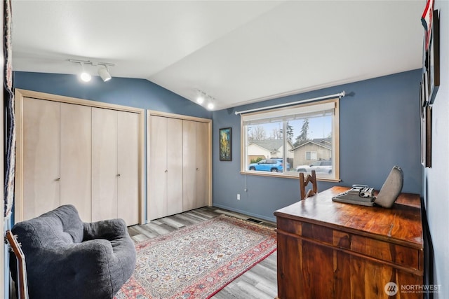 home office with lofted ceiling, rail lighting, light wood-style flooring, and baseboards