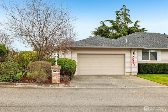 view of front of property featuring concrete driveway, roof with shingles, and an attached garage