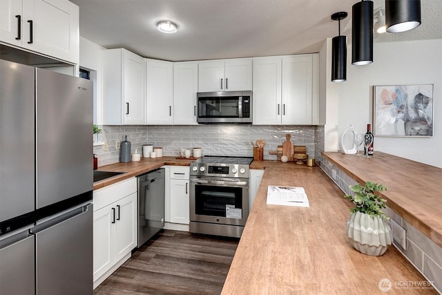 kitchen with stainless steel appliances, butcher block countertops, dark wood-type flooring, and decorative backsplash