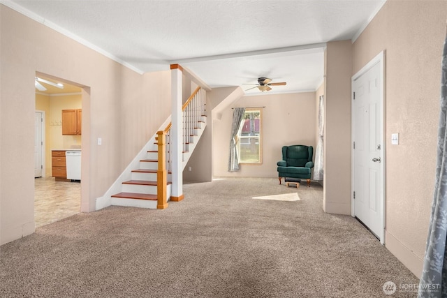 unfurnished living room with stairs, carpet flooring, a ceiling fan, and crown molding