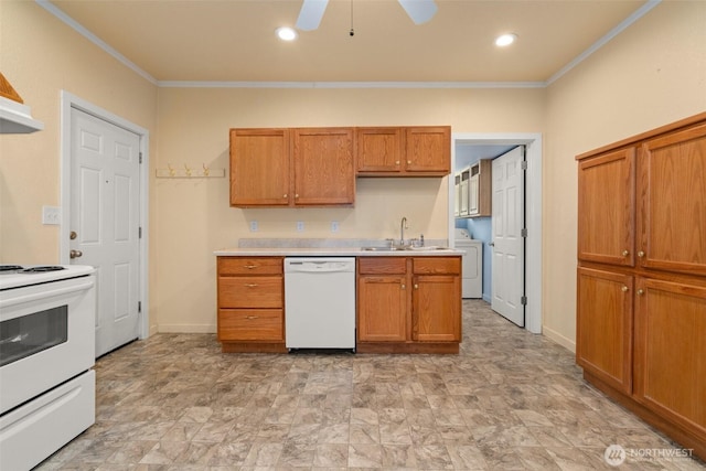 kitchen with white appliances, washer / dryer, light countertops, crown molding, and a sink