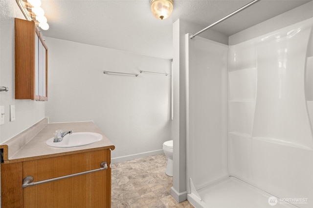 full bath featuring baseboards, vanity, toilet, and walk in shower