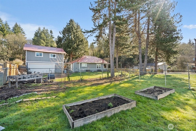 view of yard featuring a garage, a vegetable garden, and fence