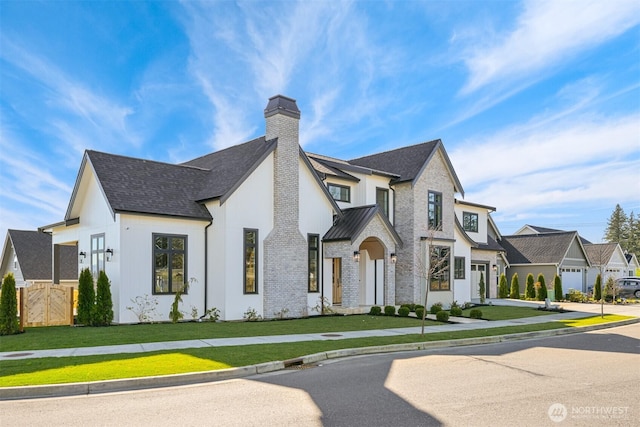 view of front of home featuring a residential view, roof with shingles, a front yard, brick siding, and a chimney