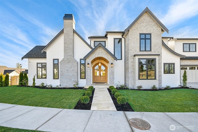 modern inspired farmhouse with a front yard, french doors, brick siding, and a chimney