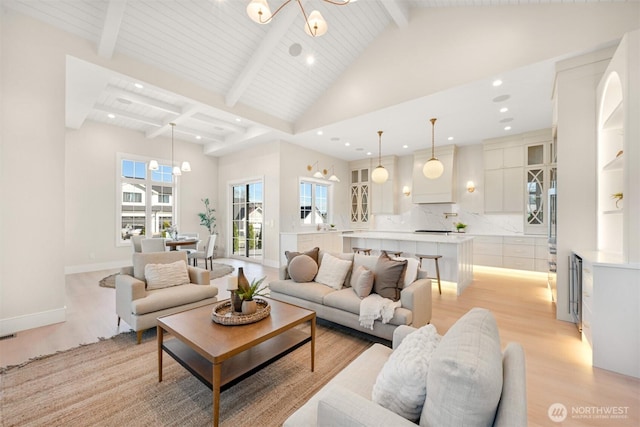 living area featuring baseboards, high vaulted ceiling, light wood-style floors, beamed ceiling, and a chandelier